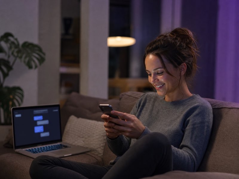 A woman exchanging real-time messages across her phone and laptop